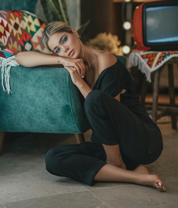 Woman in a calm, focused pose in a room with soft, natural light.